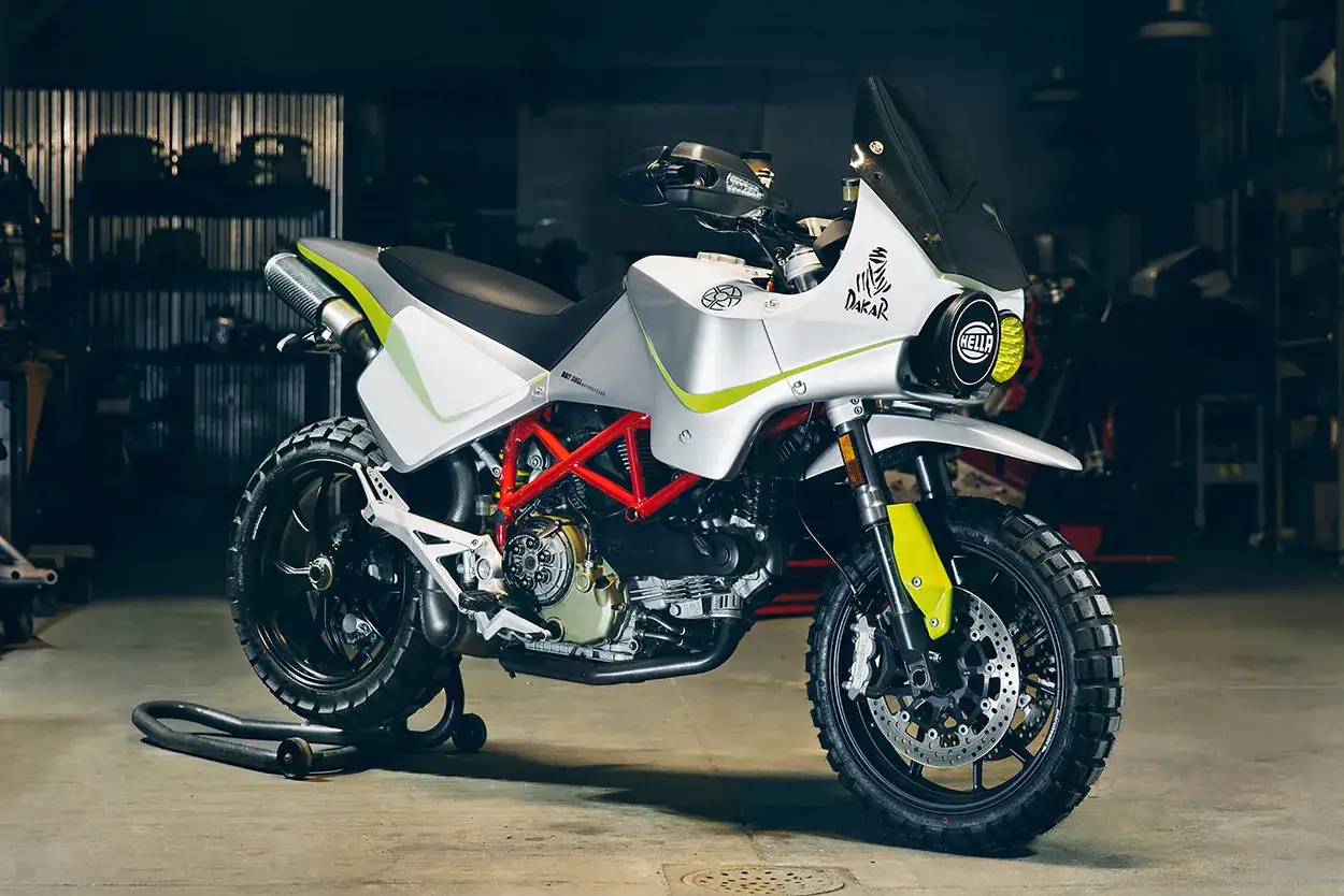 Ducati customizzata per il Dakar, con livrea bianca e verde fluo, cerchi a raggi e pneumatici tassellati. Pronta per l'avventura.