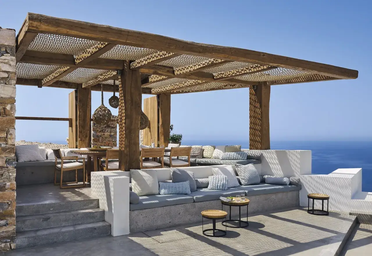 Porches sencillos y bonitos con asientos de hormig&oacute;n, cojines, mesa de madera y vistas al mar.