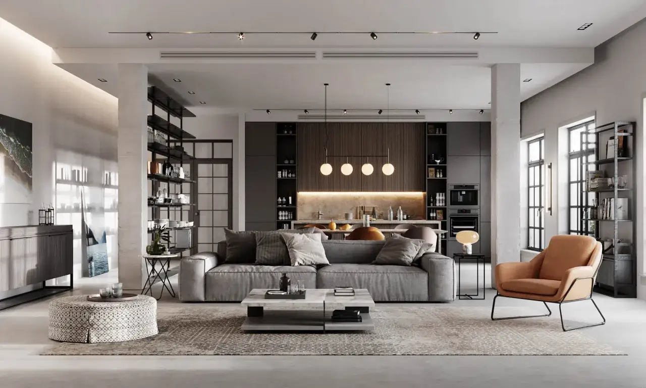 Salón moderno con sofá gris, mesa de centro geométrica y sillón ocre. Las **últimas tendencias en iluminación de salones** se aprecian en los focos del techo y la lámpara colgante sobre la isla de cocina.
