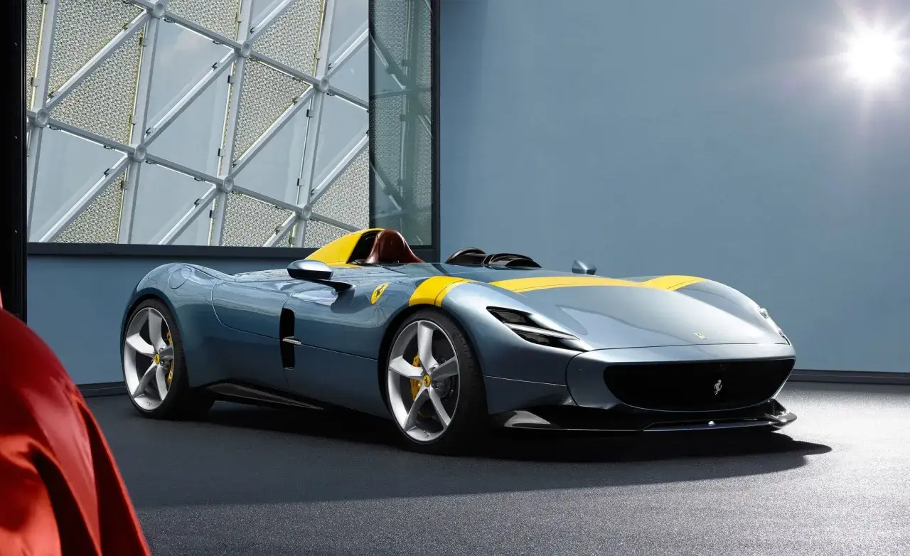 Niebieski Ferrari Monza SP1 z żółtymi pasami, sportowy roadster, gotowy do jazdy po torze.