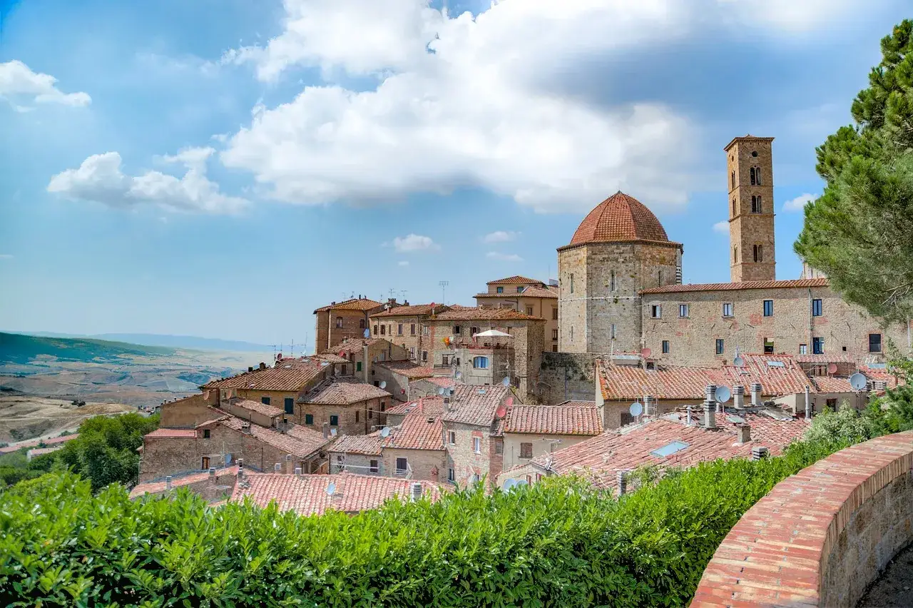 Panoramica di Volterra, con la sua antica pietra che racconta storie, dominata da un duomo con cupola rossa e un campanile svettante.