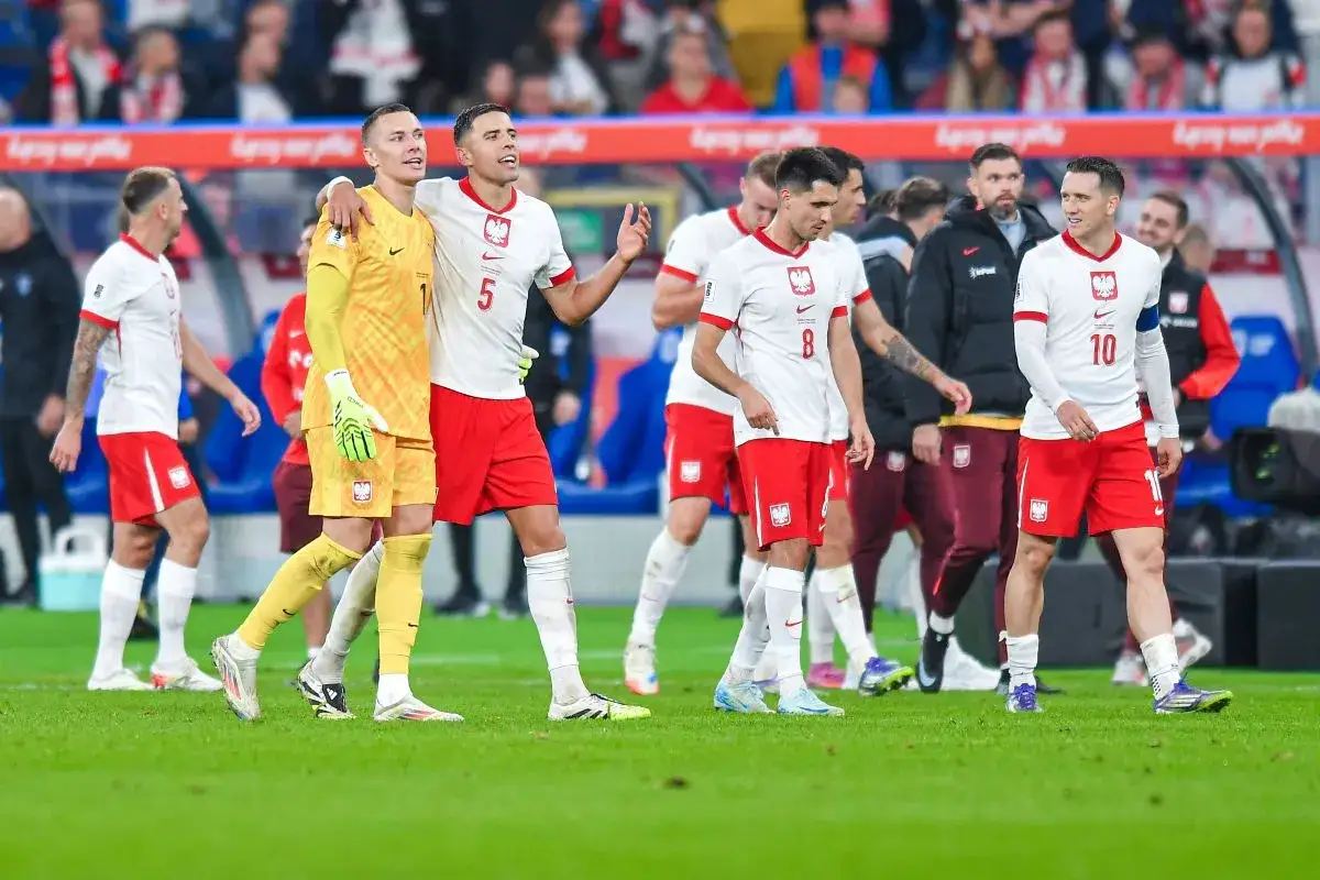 Piłkarze Polski w białych koszulkach i czerwonych spodenkach, w tym bramkarz w żółtym stroju, idą po boisku. Emocje po meczu Polska-Finlandia.