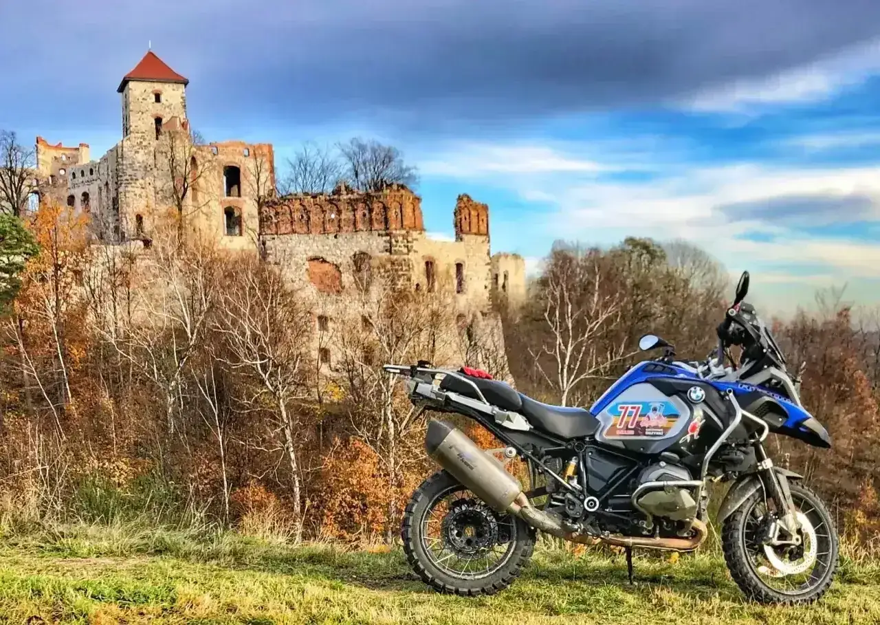 Motocykl gotowy na jednodniowy wypad motocyklowy. W tle ruiny zamku i jesienne drzewa.