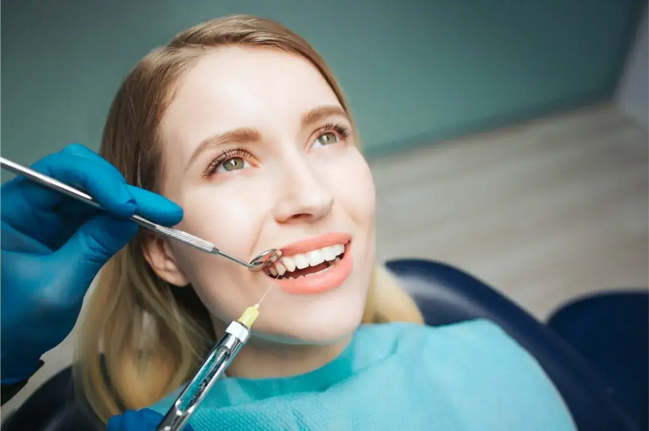 Uśmiechnięta pacjentka u dentysty, zastanawia się, czy po znieczuleniu u dentysty można prowadzić samochód.