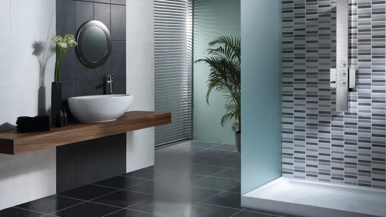 Salle de bain moderne avec lavabo sur meuble flottant en bois, miroir rond, douche à l'italienne avec panneau mosaïque. Le sol brillant et le **ragréage étanche** complètent le design.