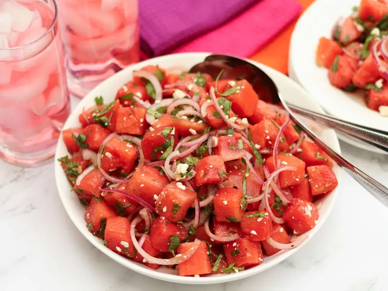 En uppfriskande melon och fetaostsallad med r&ouml;dl&ouml;k och mynta, serverad i en vit sk&aring;l. Perfekt sommarbuff&eacute;!