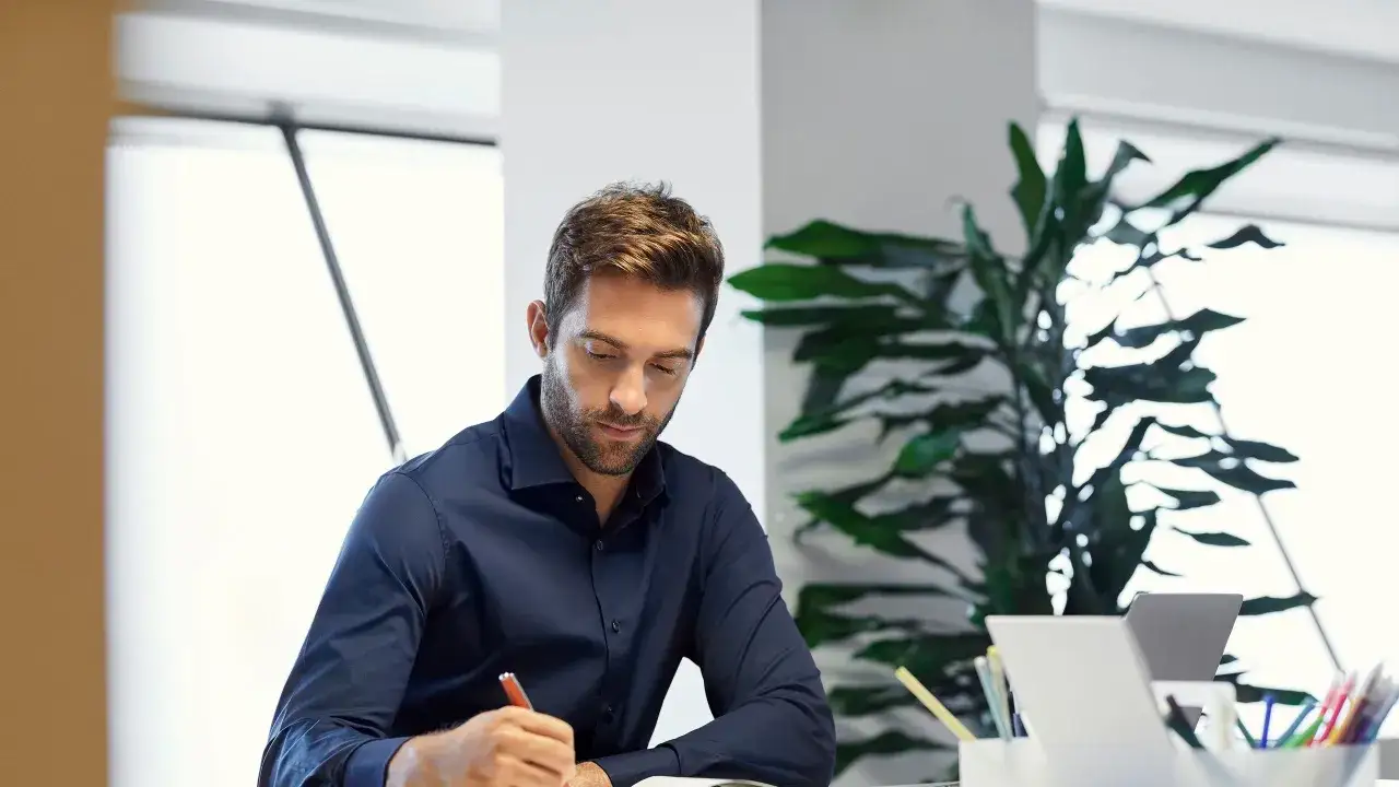 Hombre concentrado escribiendo, luchando contra un di&aacute;logo interno negativo.