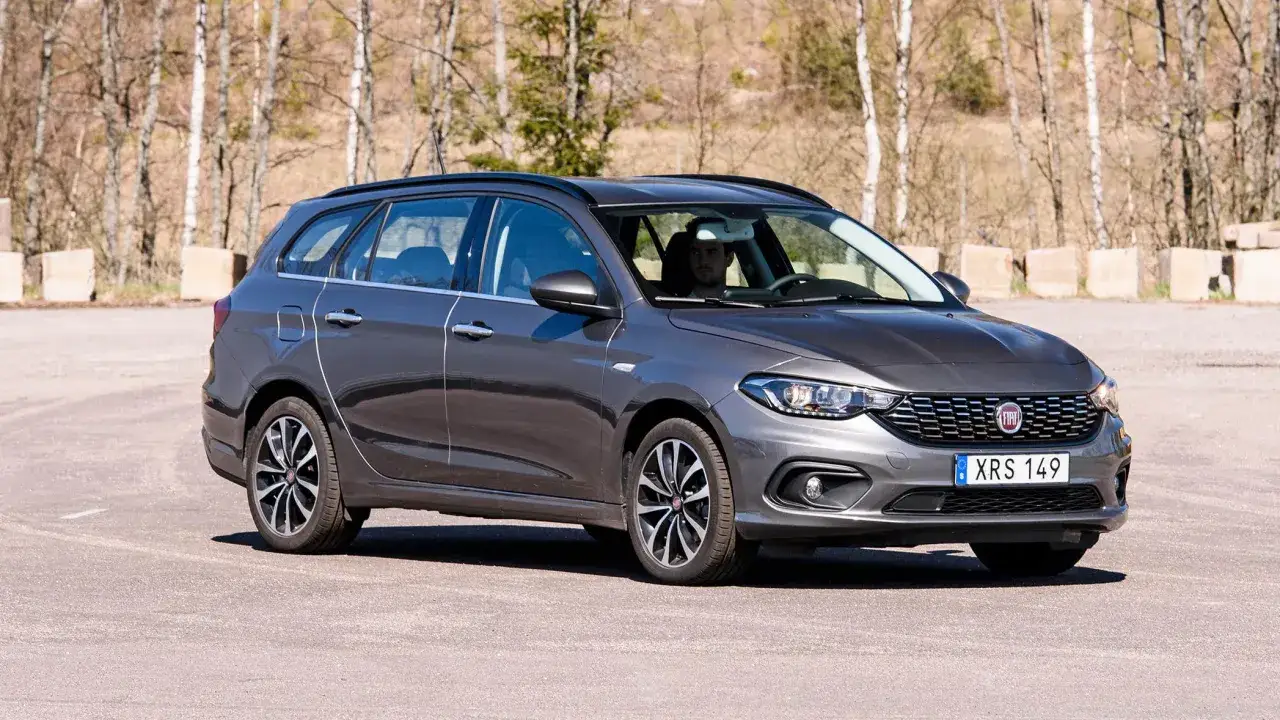 En mörkgrå Fiat Tipo kombi står parkerad utomhus. Bilen har en man bakom ratten.
