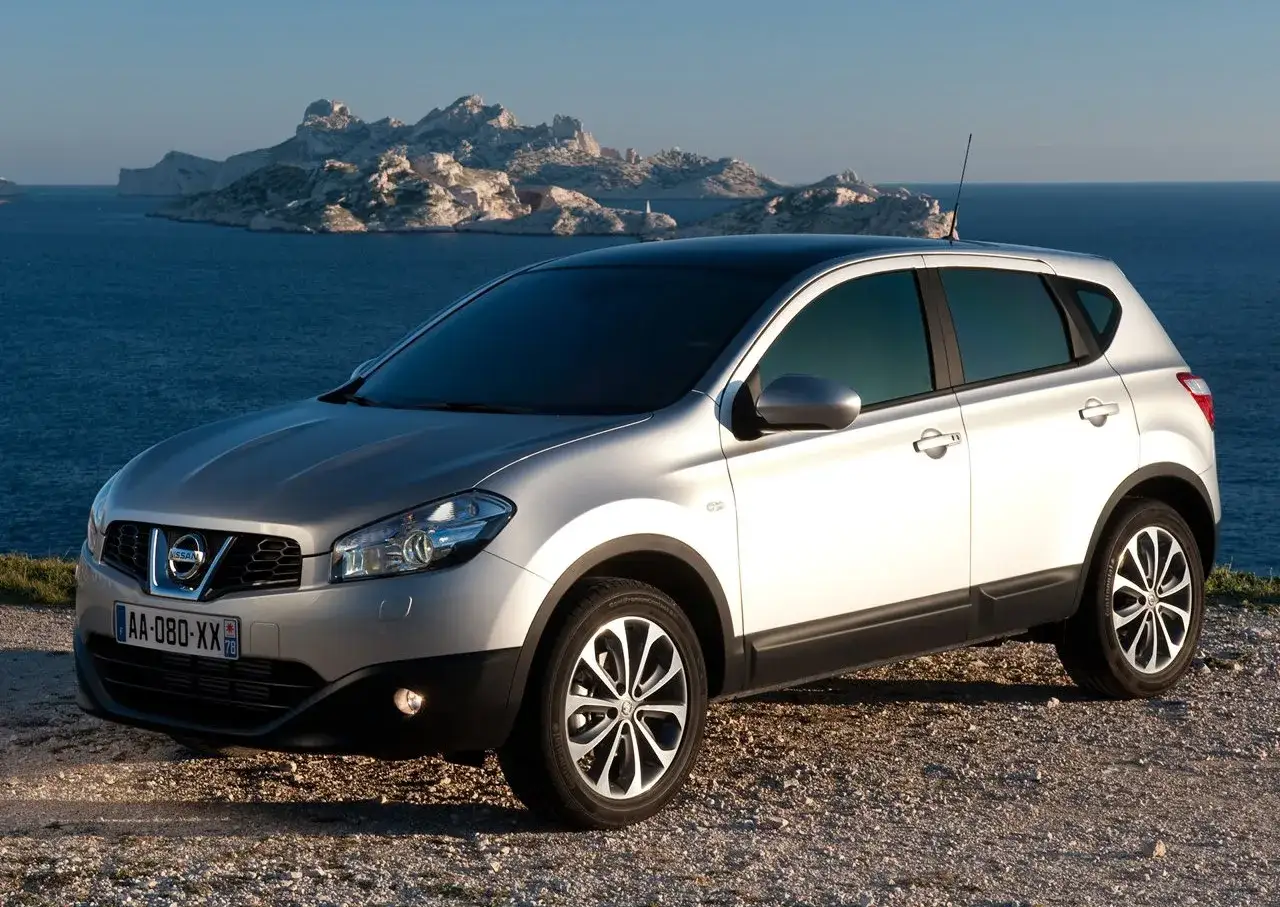Srebrny Nissan Qashqai 1 na tle skalistych wysp i morza.