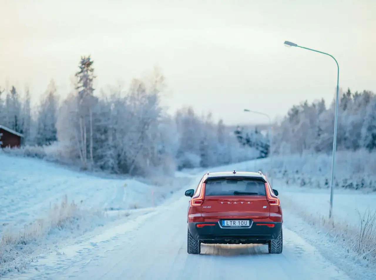 R&ouml;d Volvo XC40 k&ouml;r p&aring; en sn&ouml;ig v&auml;g, redo f&ouml;r resan fr&aring;n Stockholm till Oslo. Vinterlandskap med frostiga tr&auml;d.