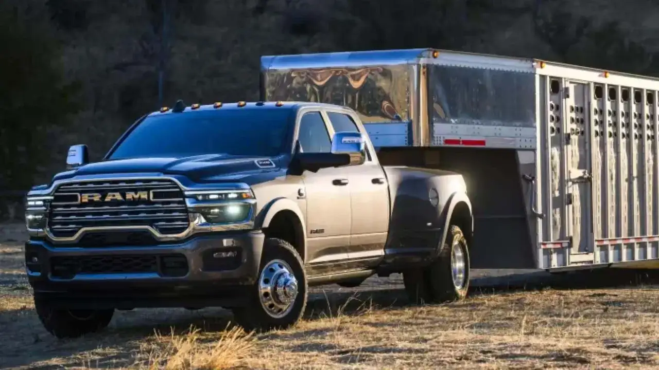 Ciemny Dodge Ram 3500 z podwójnymi tylnymi kołami holuje przyczepę z bydłem.