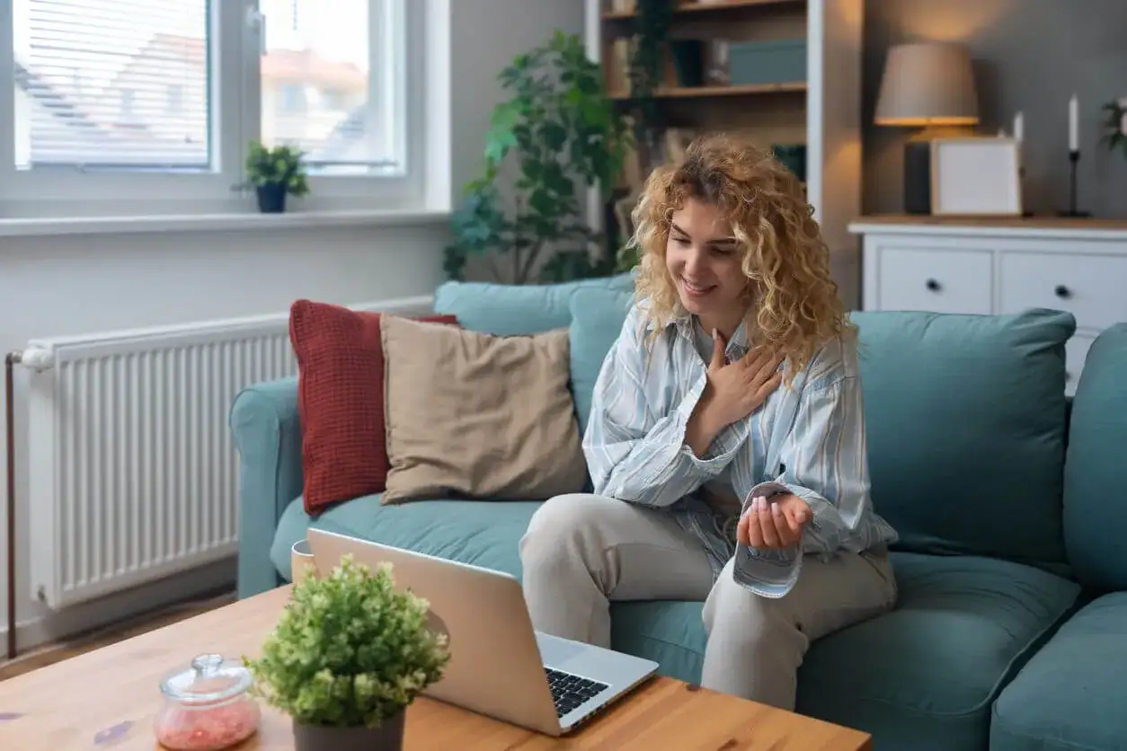 Kobieta z kręconymi włosami uśmiecha się, prowadząc terapię schematów online z domu.