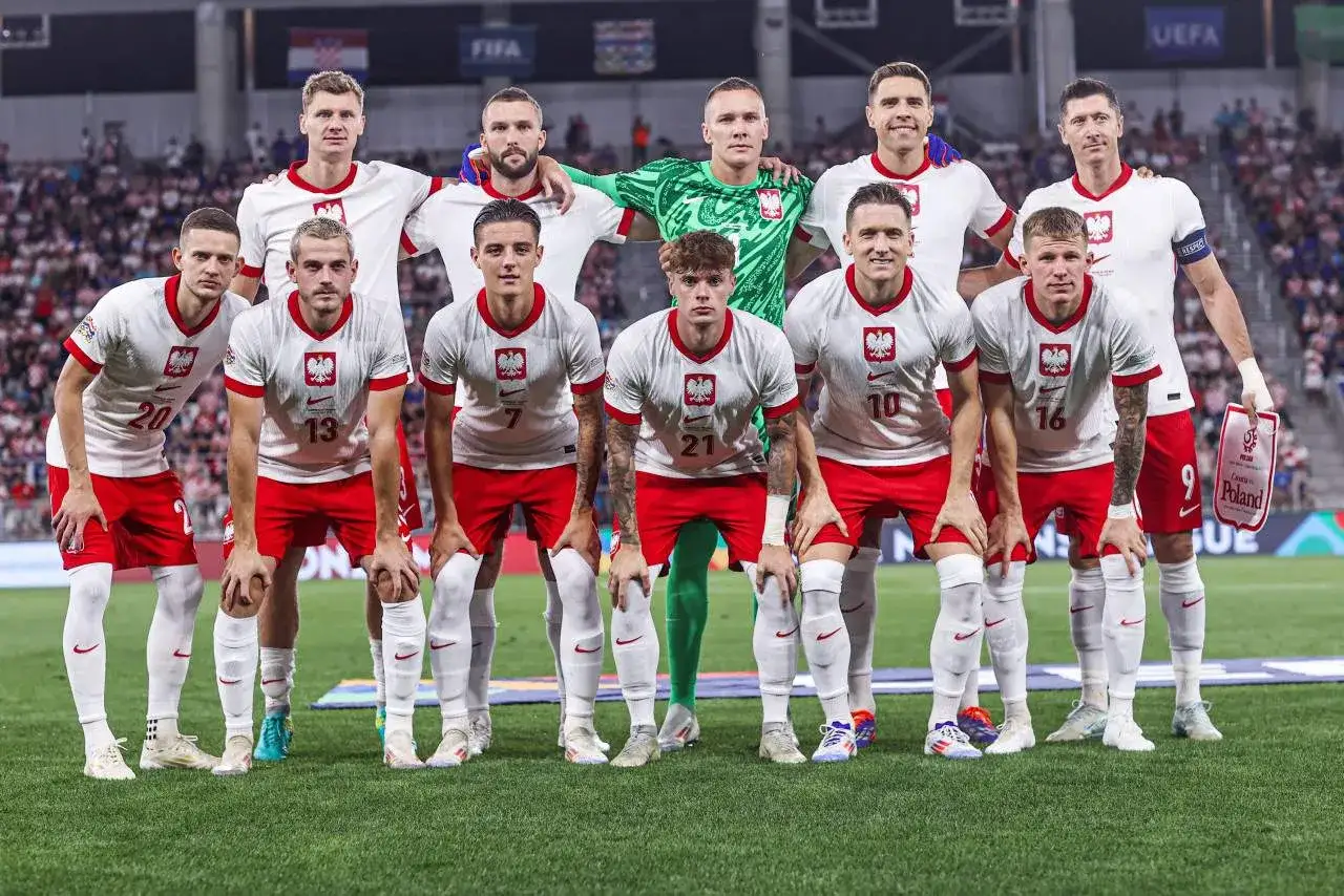 Piłkarze reprezentacji Polski w białych strojach, gotowi do gry. Czy wśród nich jest ten, kto ma najwięcej mistrzostw Polski?
