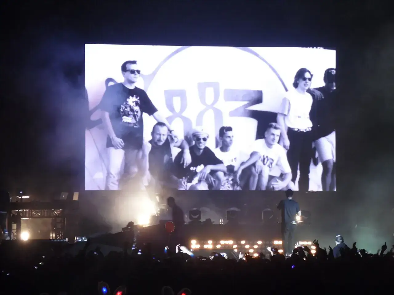 Schermo gigante con il logo 883 e i membri della band. Pubblico in delirio sotto il palco.