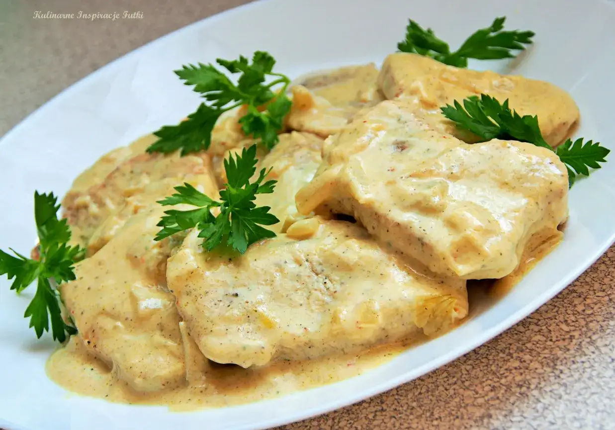 Pyszny filet z indyka w sosie śmietanowym, udekorowany natką pietruszki. Idealny na obiad.