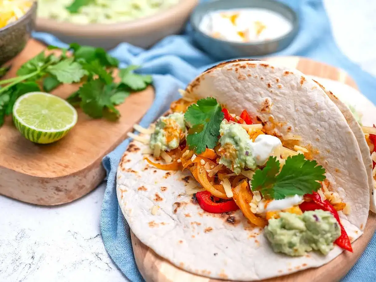 Två läckra tacos med guacamole, ost och färsk koriander. Perfekt för att lära sig como hacer tacos.