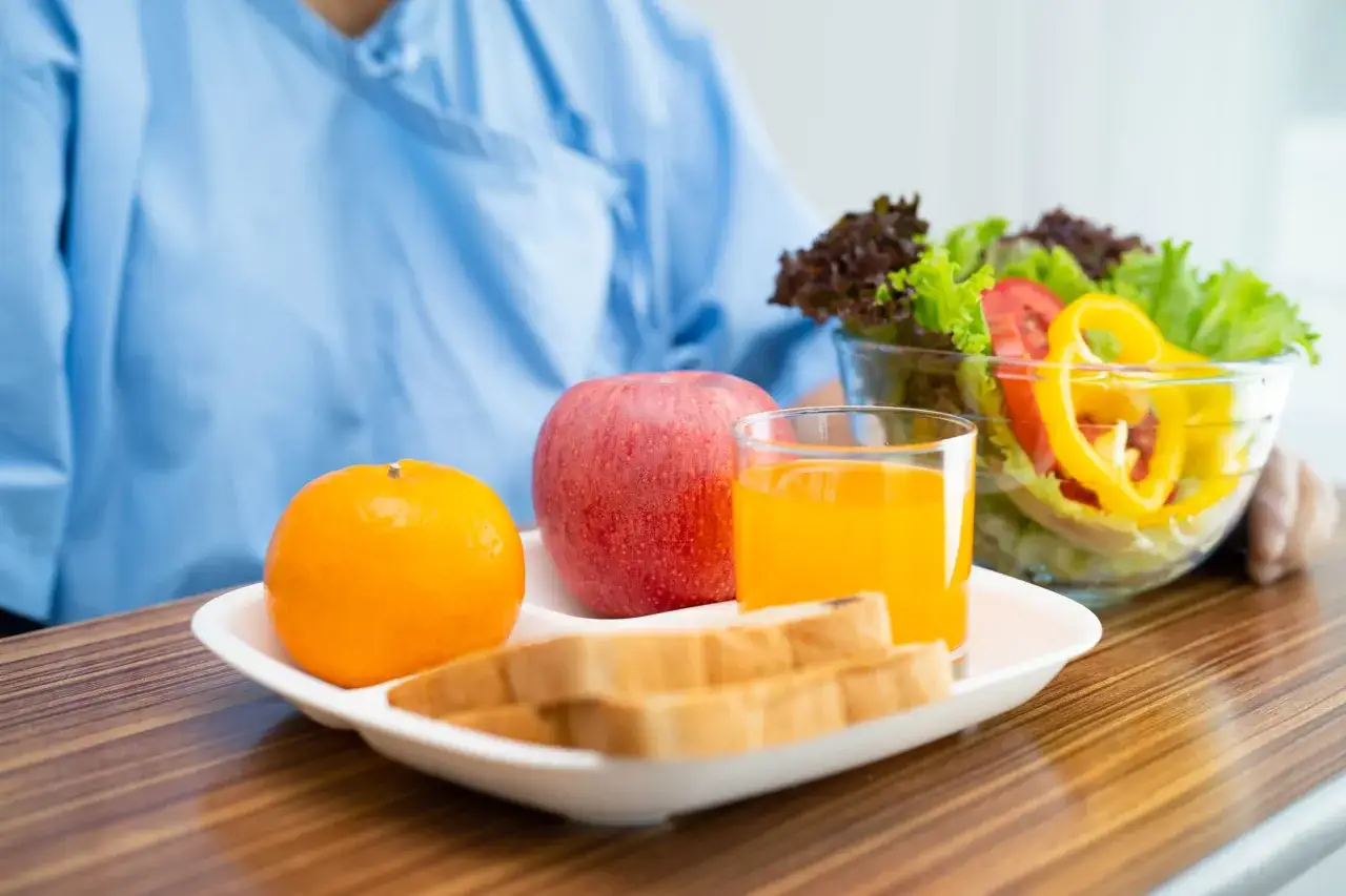 Posilek po gastroskopii: pomarańcza, jabłko, sok, tosty i sałatka.