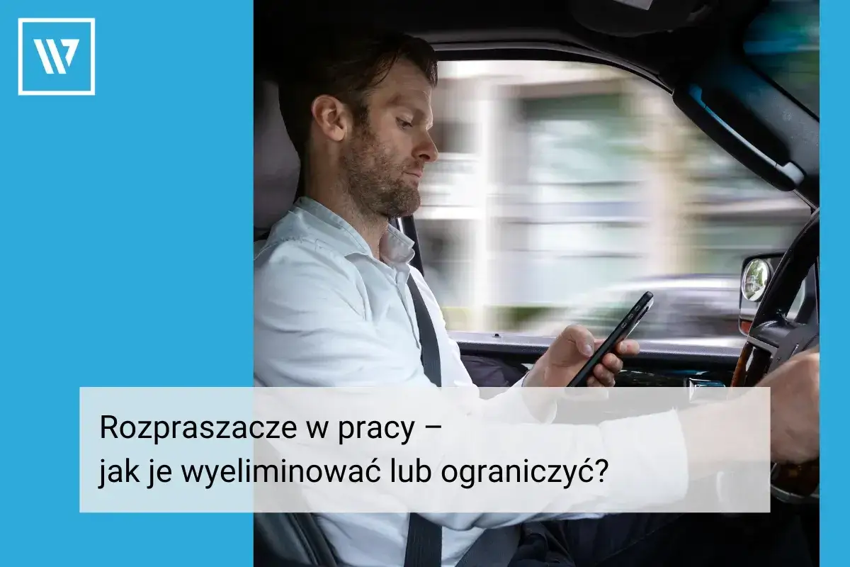 Mężczyzna w samochodzie patrzy na telefon, co najbardziej rozprasza człowieka w pracy. Jak ograniczyć rozproszenia?