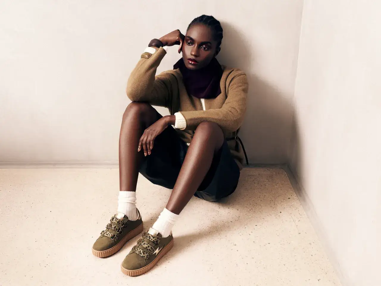 Une femme pose, assise, avec des baskets vertes femme stylées. Un look décontracté et tendance.