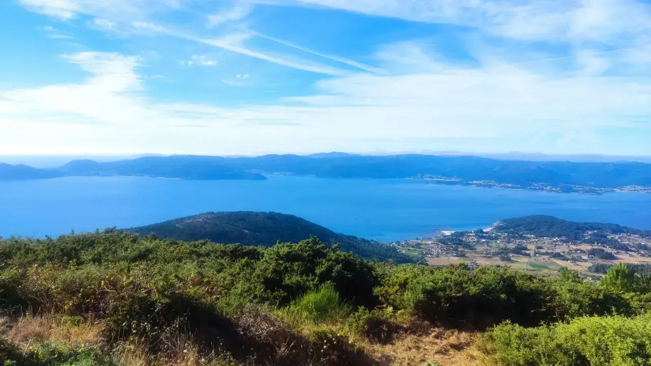 Vista panorámica desde el monte Enxa, con el mar azul intenso y montañas al fondo.
