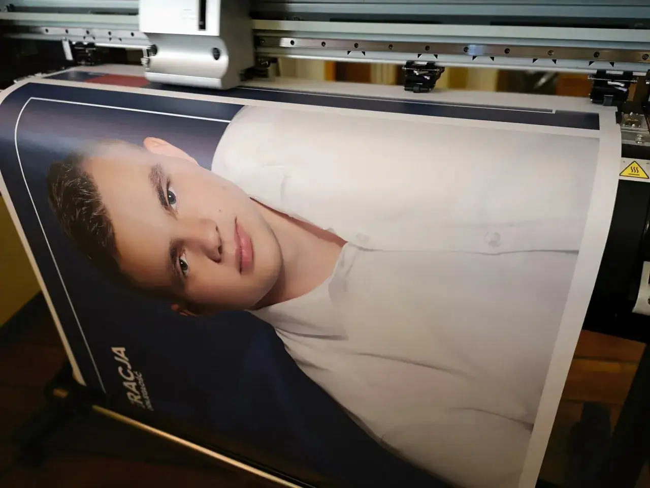 Ploter drukuje portret młodego mężczyzny na plakacie wyborczym.