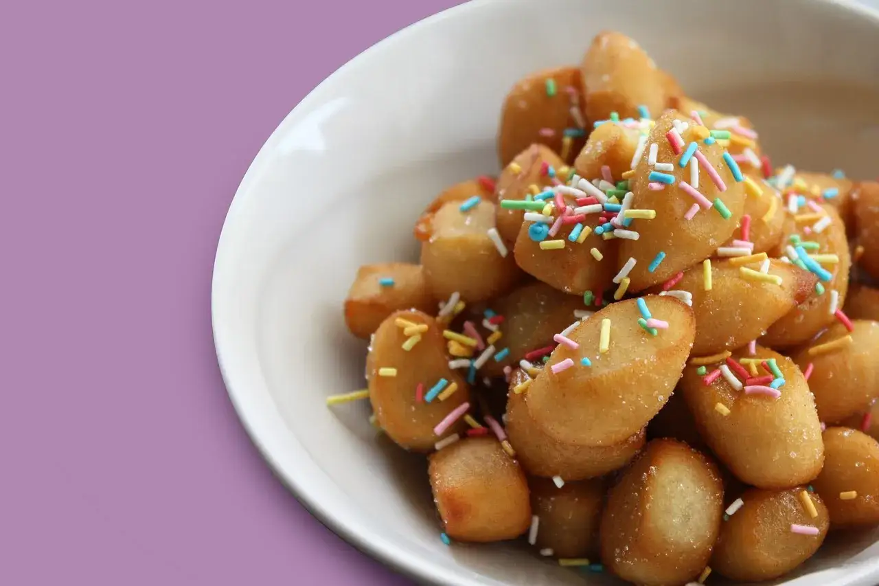 Un piatto di dolci tipici pugliesi, piccole palline dorate cosparse di zuccherini colorati, invitano a un assaggio di tradizione.