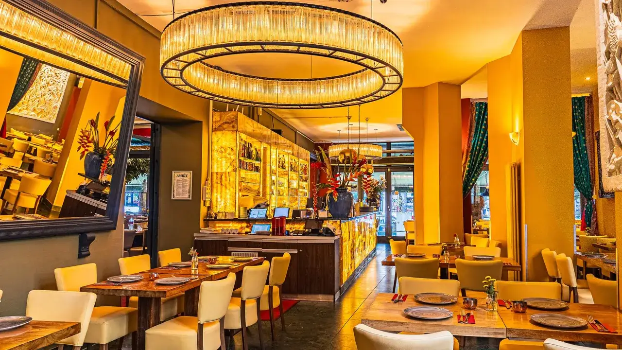 Elegantes Interieur eines Restaurants in Berlin mit gelben Stühlen, Holztischen und einer beleuchteten Bar.