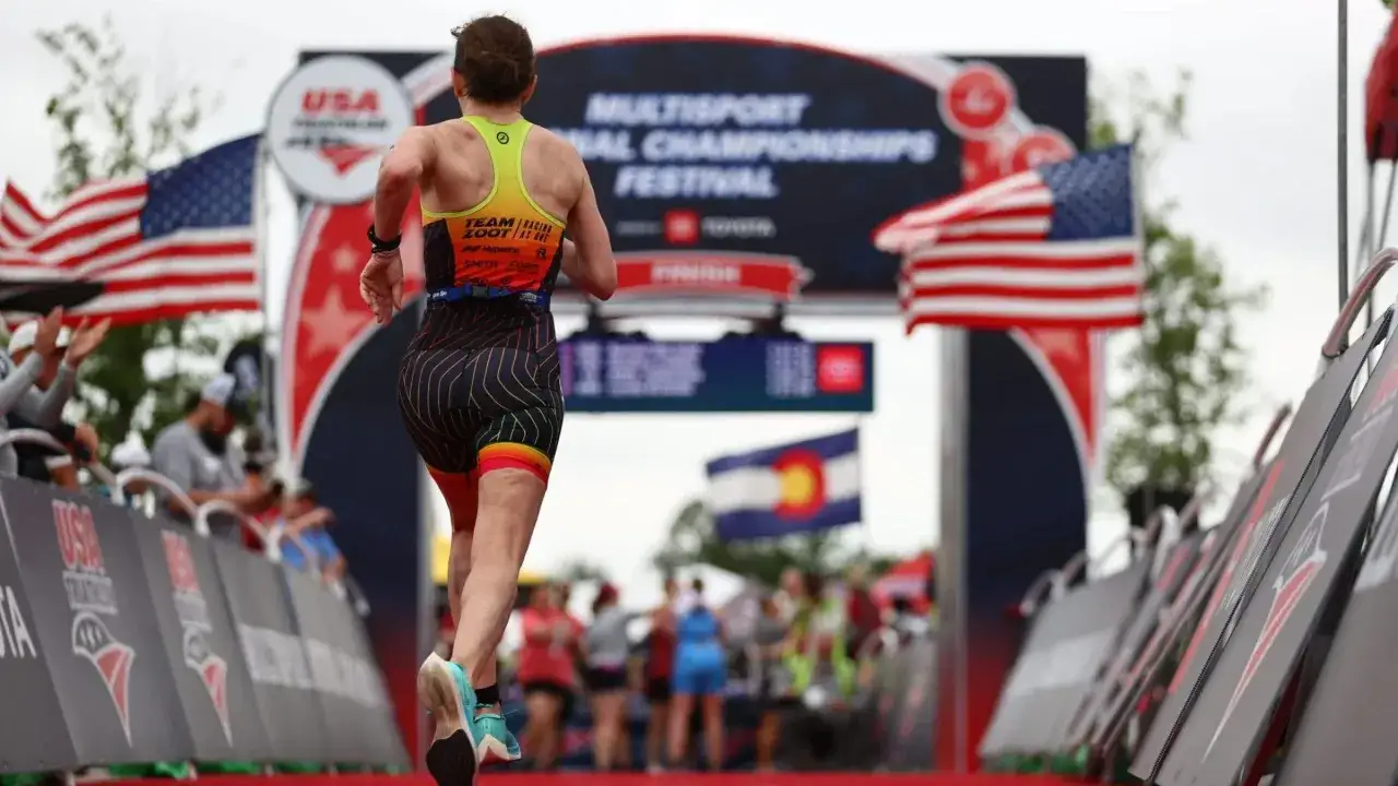 A triathlete crosses the finish line at the USA Triathlon Multisport National Championships Festival, a testament to their USA Triathlon membership.