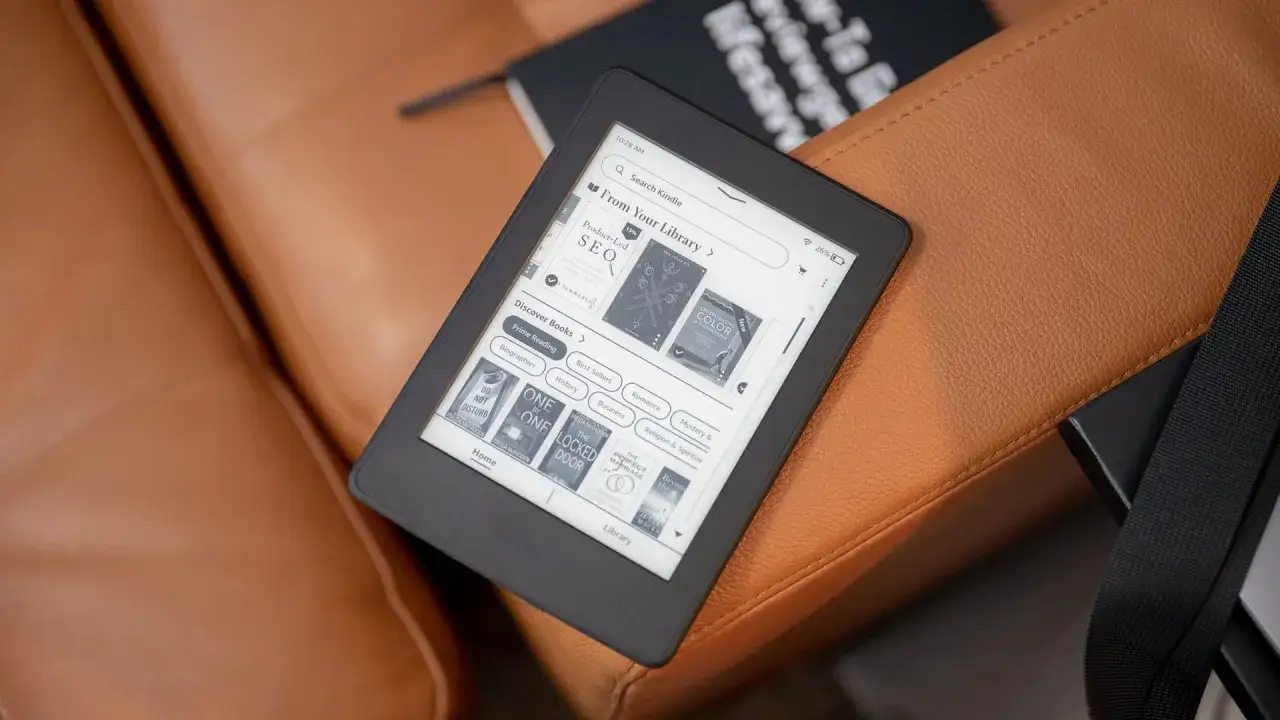 Un Kindle sur un canap&eacute; en cuir marron, pr&ecirc;t &agrave; ajouter un nouveau livre.