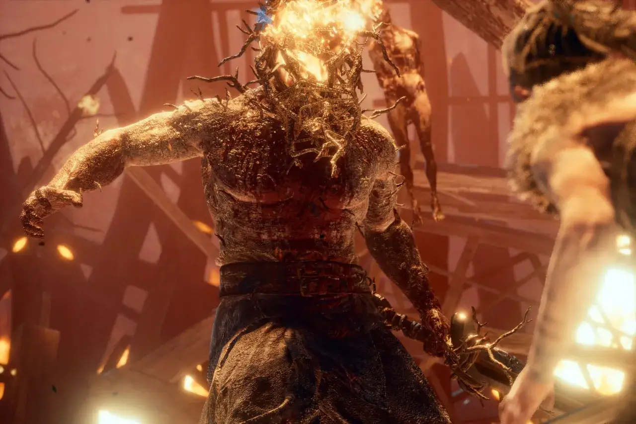 Potężna, płonąca postać z Hellblade: Senua's Sacrifice, z gałęziami wyrastającymi z ciała, walczy w mrocznym świecie.