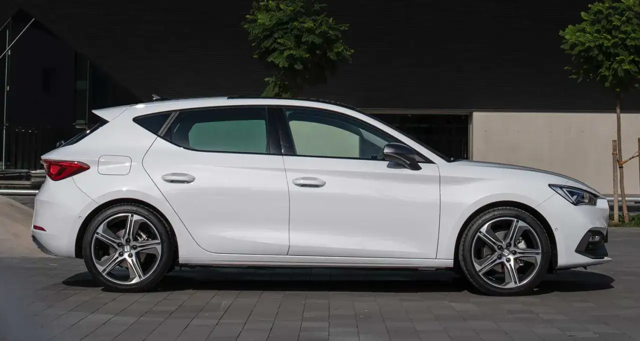 Un coche blanco deportivo, modelo FR, estacionado frente a un edificio moderno.