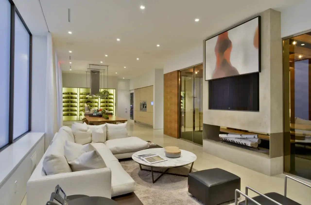 Modernes Wohnzimmer mit gro&szlig;em Sofa, Kamin und einem Kunstwerk &uuml;ber dem Fernseher, der sich geschickt im Design verstecken l&auml;sst.
