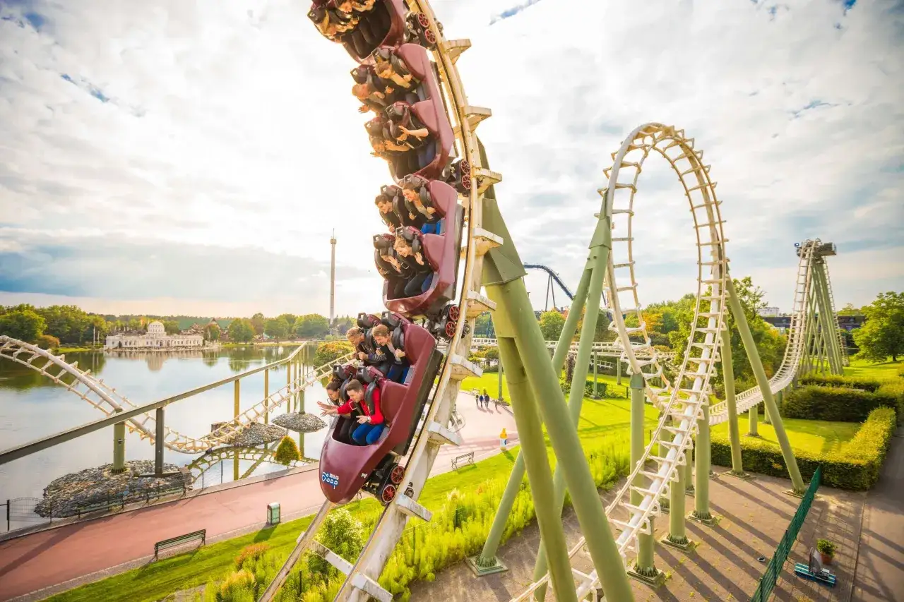 Ekscytujące atrakcje w Heide Park: wagoniki kolejki górskiej pędzą w dół, a pasażerowie krzyczą z radości.
