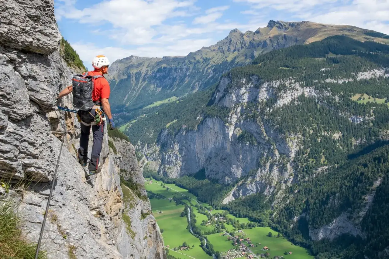 Wspinacz na via ferrata w Szwajcarii podziwia zapierający dech w piersiach widok na dolinę.