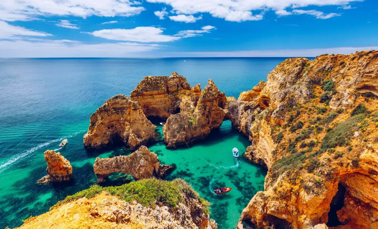 Skały w Algarve, turkusowa woda i łodzie. Piękna faro pogoda listopad, idealna na wycieczkę.