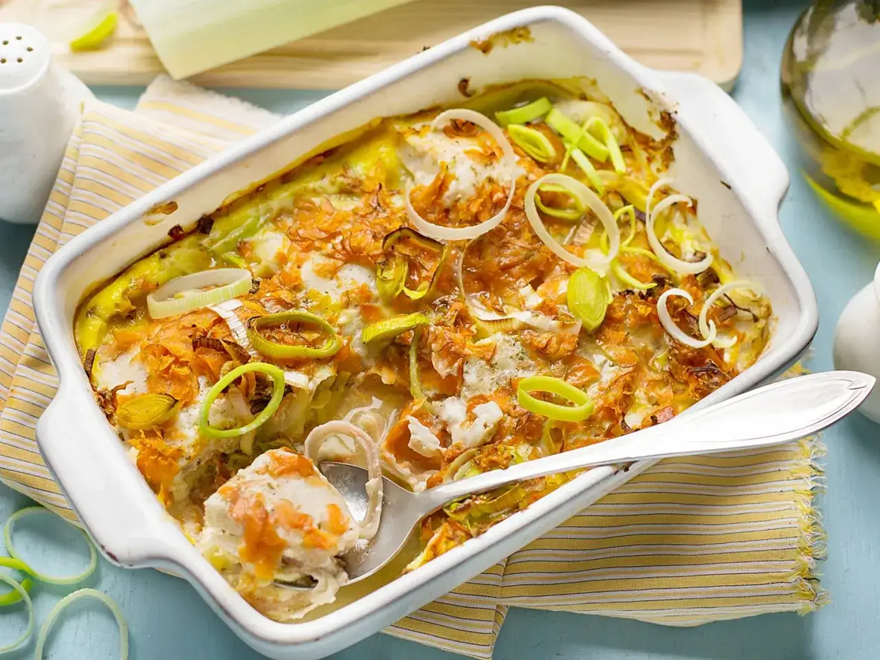 Un plat gratiné de poireaux au jambon, garni de rondelles de poireaux frais et de fines tranches de carottes.