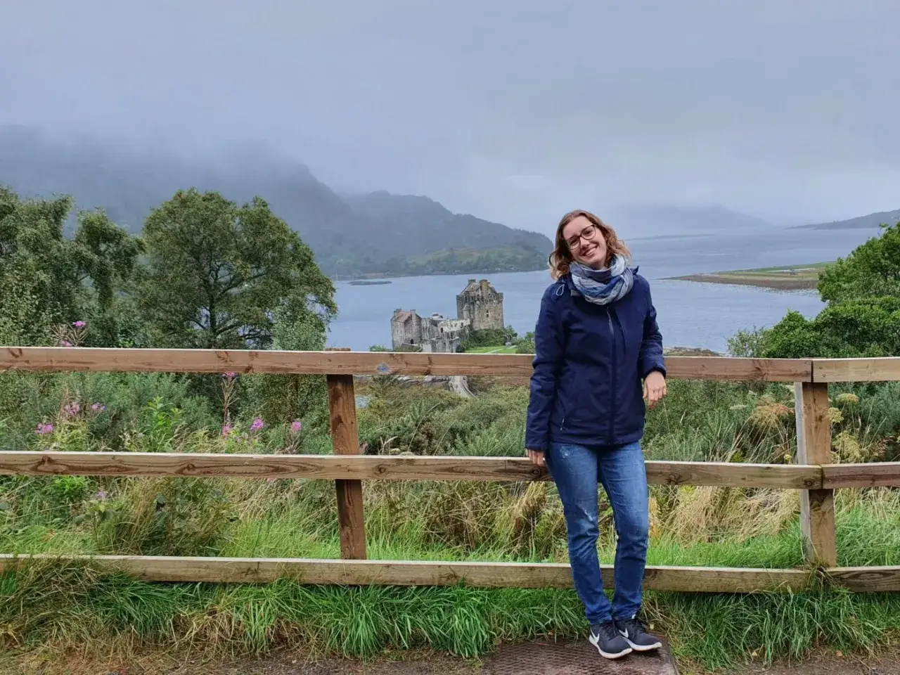 Frau vor schottischer Burg bei typischem Septemberwetter. Die Landschaft ist gr&uuml;n, das Wetter schottland september ist wechselhaft, aber die Aussicht ist malerisch.