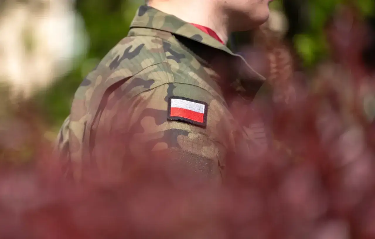 Żołnierz w mundurze moro z polską flagą na ramieniu, symbol dumy i przyszłej emerytury wojskowej.