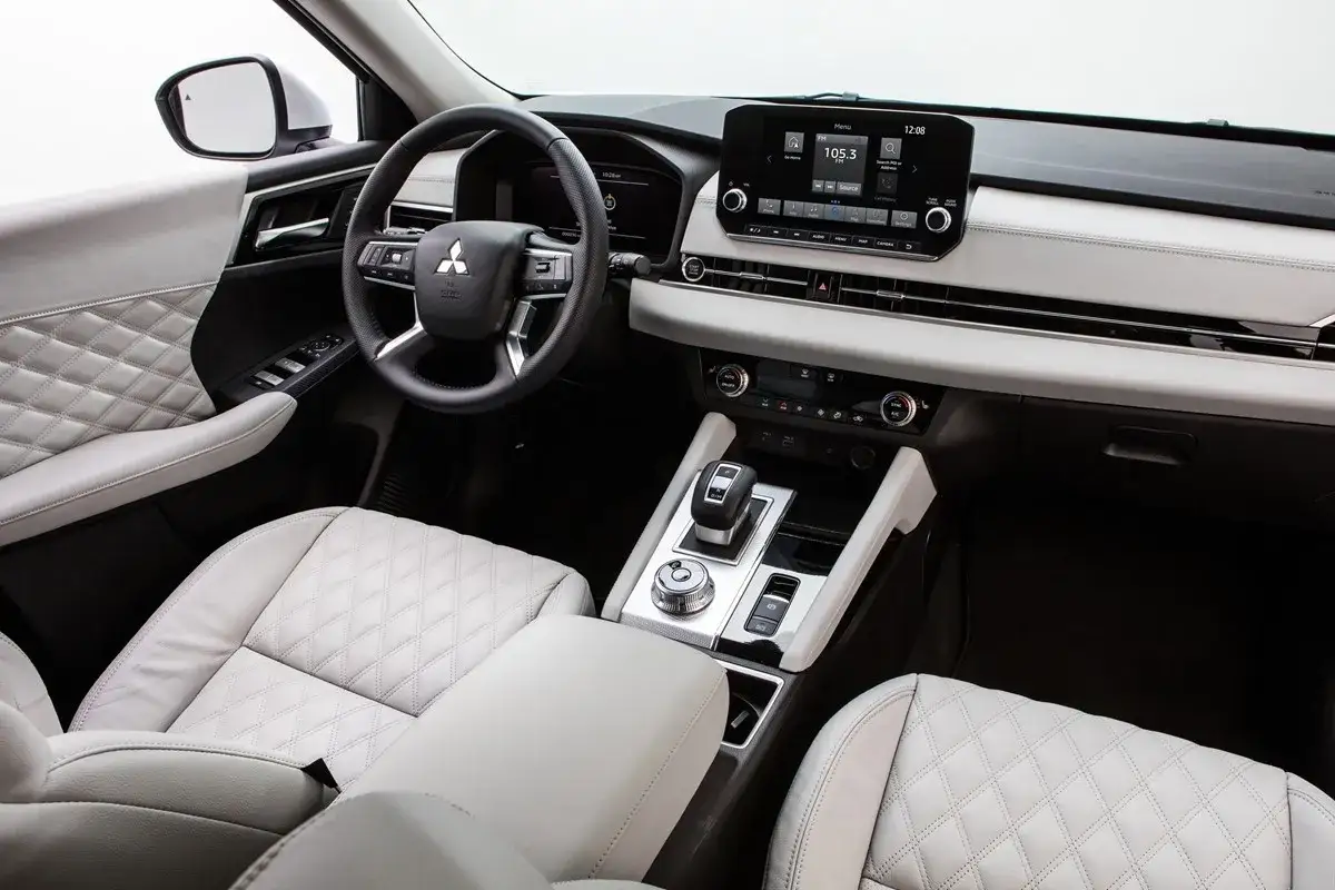 Wnętrze Mitsubishi Outlander z pikowanymi, jasnymi fotelami i nowoczesnym panelem centralnym. Wiele osób szuka mitsubishi outlander opinie, by poznać ten model.