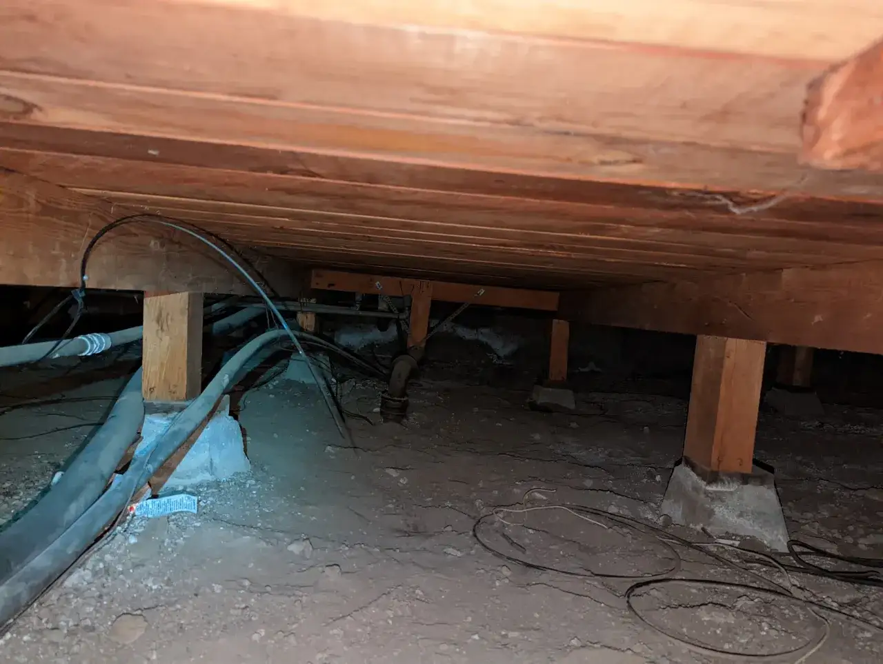 Under golvet syns tr&auml;bj&auml;lkar, r&ouml;r och kablar. En l&ouml;sning f&ouml;r att isolera golv utan att bryta upp kan vara att t&auml;ta utrymmet underifr&aring;n.