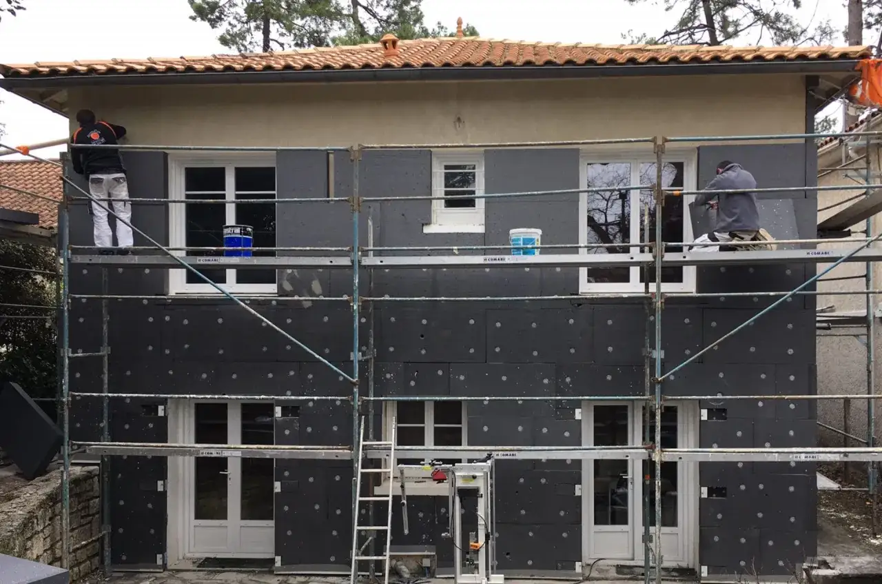 Travaux d'isolation ext&eacute;rieure pour une meilleure **efficacit&eacute; &eacute;nerg&eacute;tique maison**. Des ouvriers installent des panneaux isolants sur la fa&ccedil;ade.