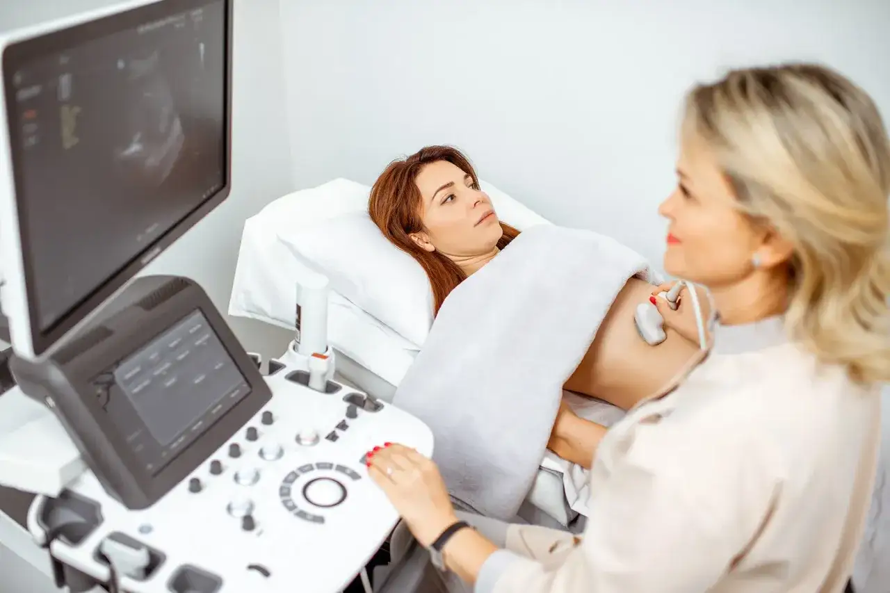 &Auml;rztin f&uuml;hrt eine gyn&auml;kologische Untersuchung mittels ku ultraschall durch. Die Patientin liegt auf einer Liege, die &Auml;rztin bedient das Ger&auml;t.