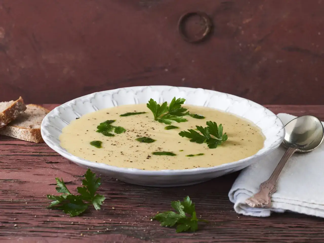 Cremige Suppe mit Petersilienwurzel-Geschmack, garniert mit frischer Petersilie und serviert mit Brot.