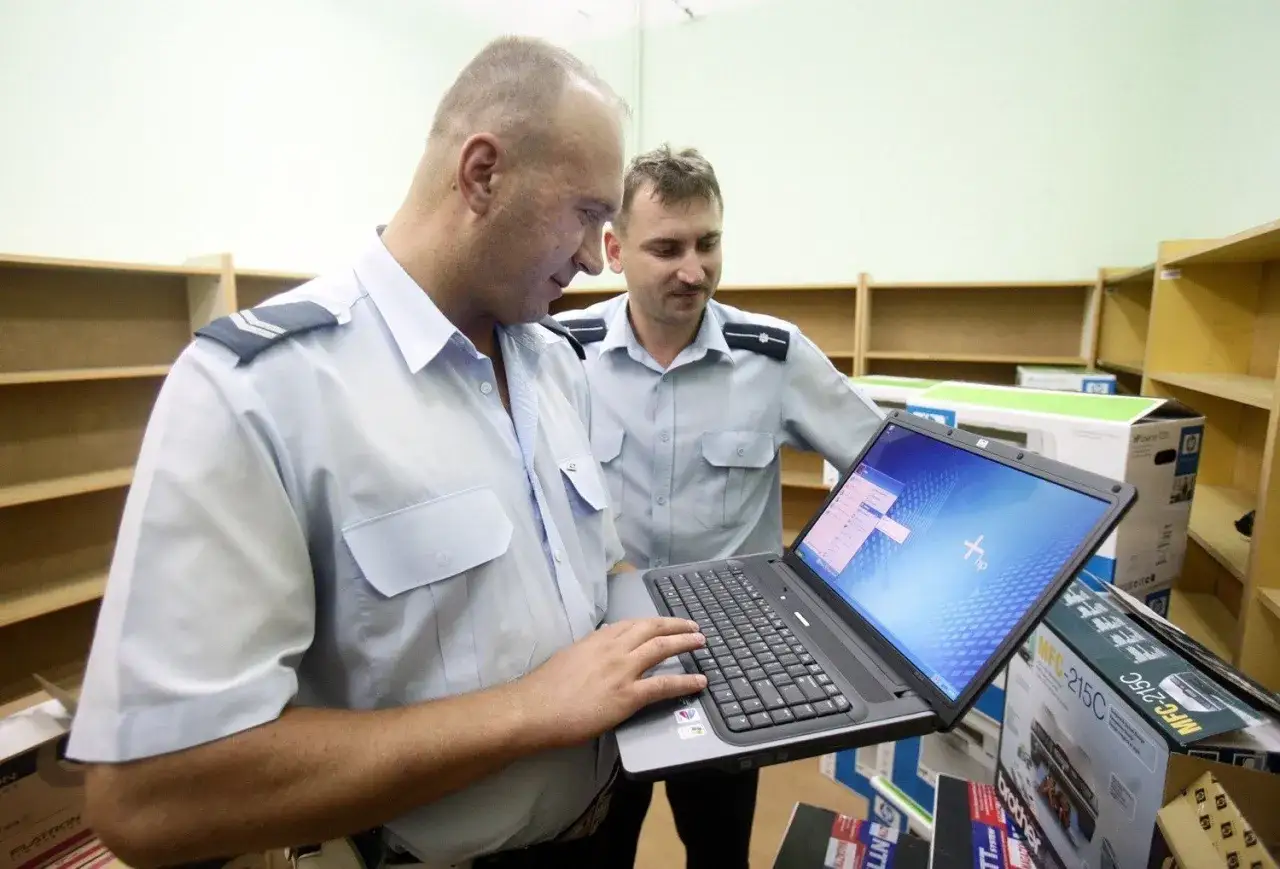 Dwóch policjantów analizuje dane na laptopie, być może przygotowując się do tego, jak napisać zgłoszenie na policję.
