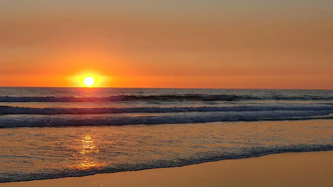 Atardecer en Conil de la Frontera. Olas doradas reflejan el sol poniente, perfecto para saber qu&eacute; hacer en Conil de la Frontera.
