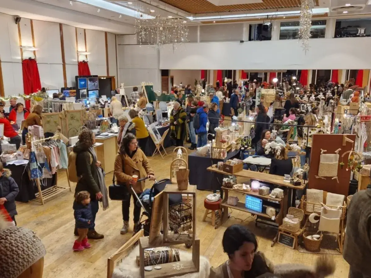Foule dans un marché de Noël, découvrant l'artisanat à Annecy. Stands remplis de créations uniques, ambiance chaleureuse.