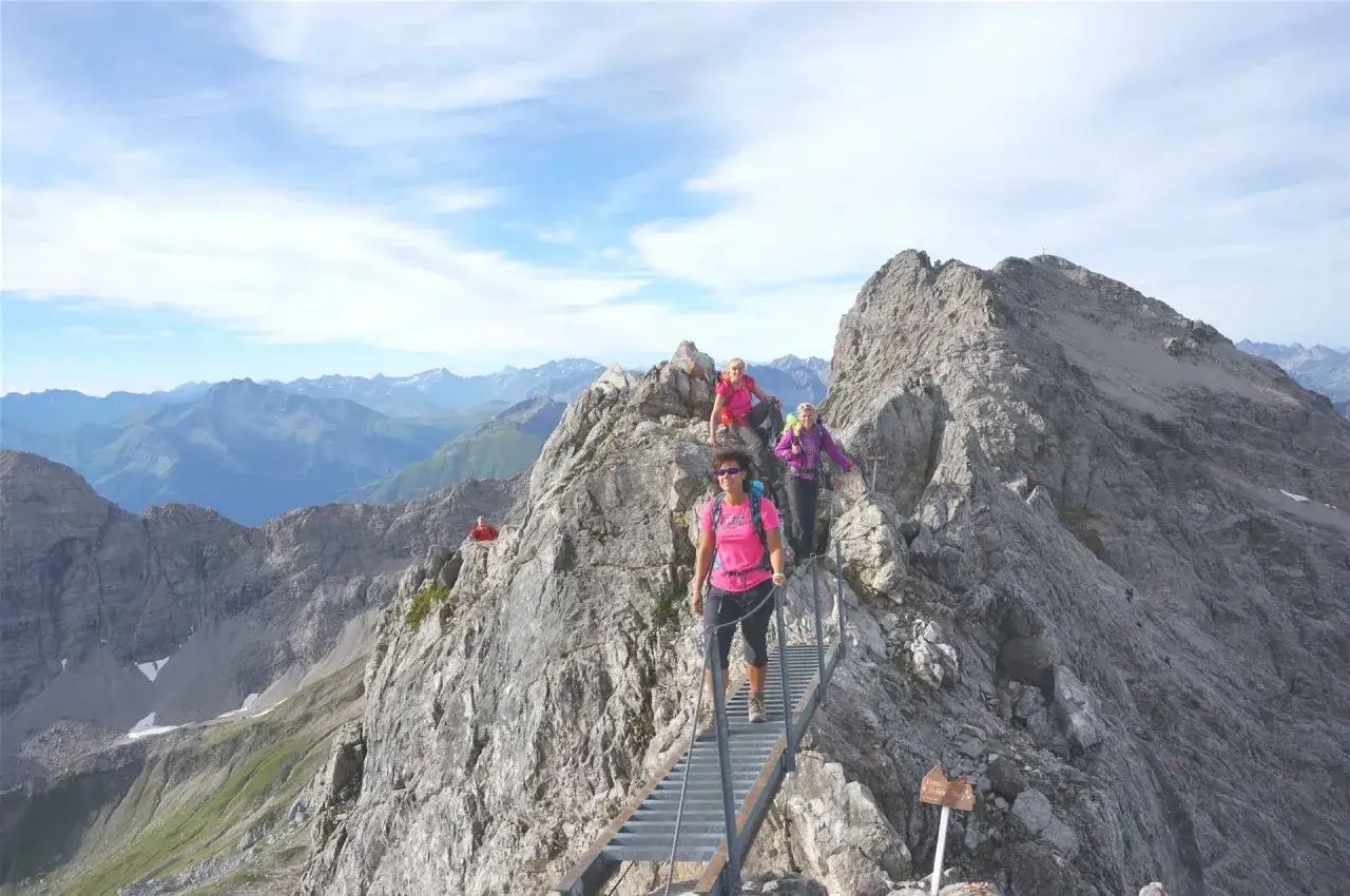 Wanderer auf dem Heilbronner Weg überqueren eine Leiterbrücke in den Alpen.