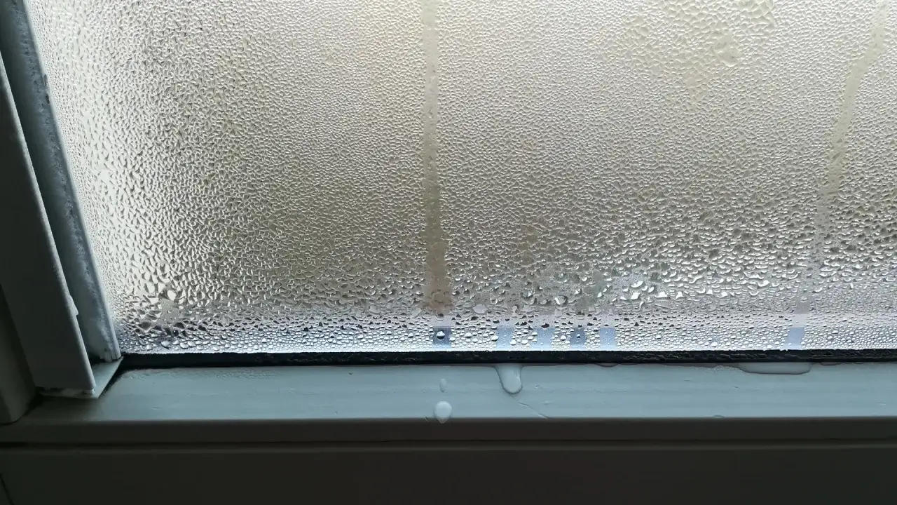 Goccioline d'acqua sul vetro, segno di umidità da condensa. L'acqua scivola lungo il serramento.