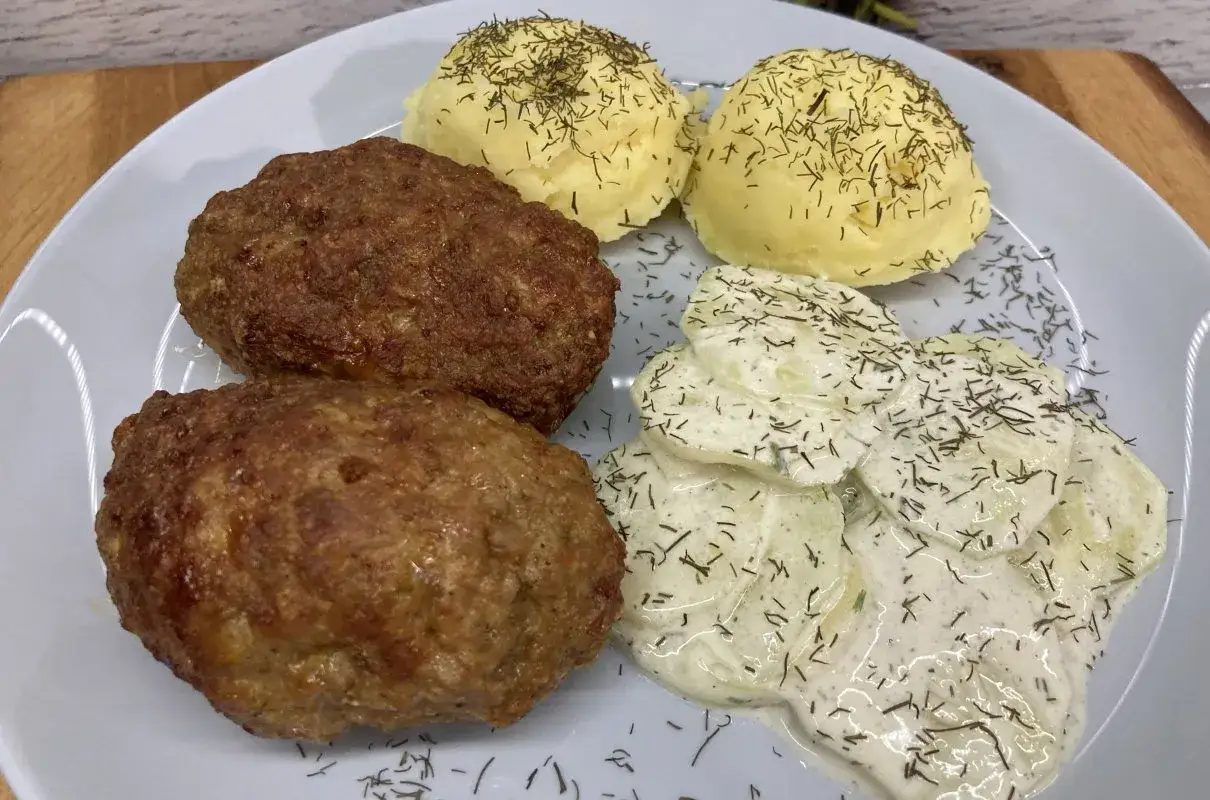 Dwa soczyste mielone z airfryera, podane z ziemniakami i mizerią, posypane koperkiem.
