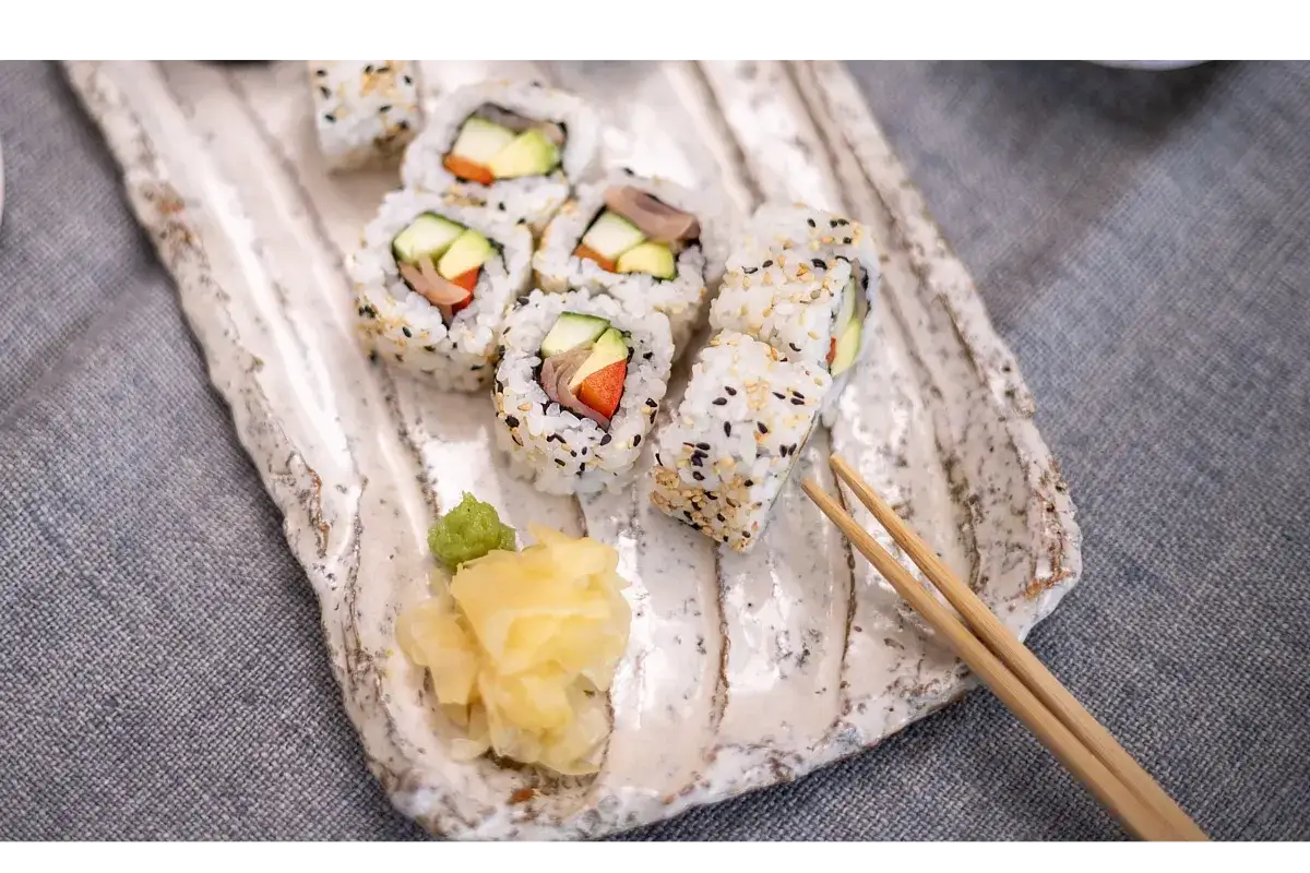 Uramaki z awokado, ogórkiem i papryką, posypane sezamem, podane z imbirem i wasabi.